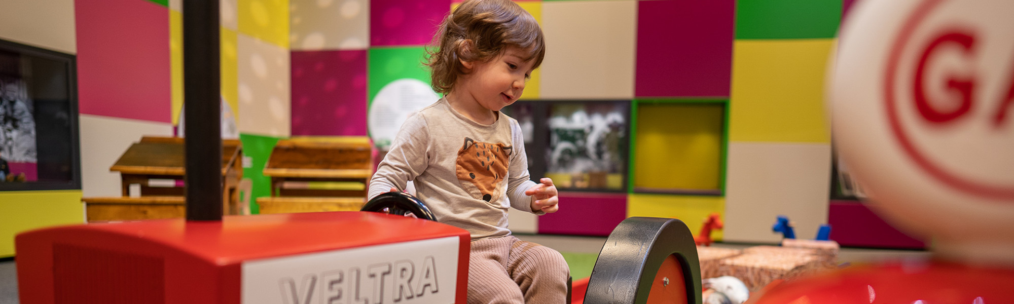 Kuvassa lapsi Leikkimössä istumassa leikkitraktorin päällä.