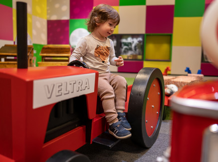 Kuvassa lapsi Leikkimössä istumassa leikkitraktorin päällä.